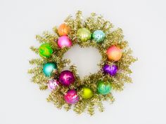 a wreath made out of christmas balls and greenery on a white background with space for text