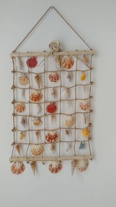 a wall hanging with seashells and rope on it's sides, in the shape of a net