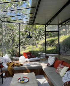 a living room filled with lots of furniture under a glass roof covered in plants and trees