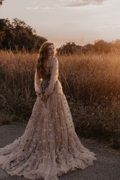 a woman wearing a dress standing in the middle of a field