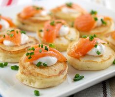 small appetizers with salmon and cream cheese are on a square white platter