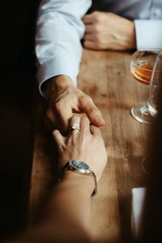 two people sitting at a table holding hands with one another and the other hand on top of each other