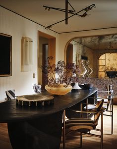 a dining room table and chairs in front of a mirror with vases on it