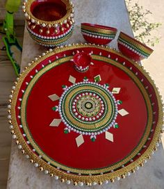 a red and gold tray with two bowls on it next to another bowl that is sitting on a table