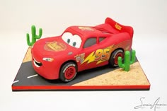 a cake shaped like the character cars from disney pixars is on display in front of a cactus