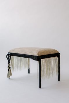 an upholstered bench with tassels on the legs