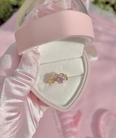 an open ring box with a pink ribbon around it