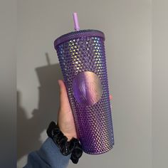 a person holding up a purple cup with a pink straw in it's mouth