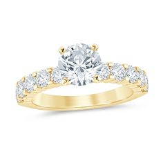 a yellow gold engagement ring with three stones on the band and an oval cut diamond