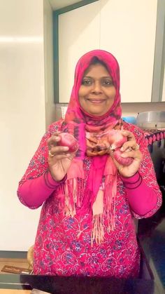 a woman in a pink scarf is holding some food and posing for the camera with her hands