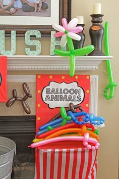 balloon animals and balloons in front of a fire place with a sign that says balloon animals