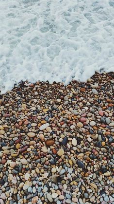 there is a surfboard sitting on the rocks by the water's edge with waves coming in