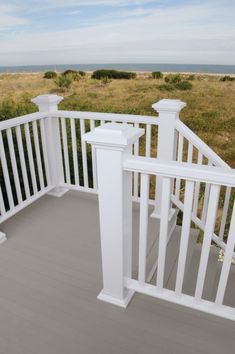 a porch with white railings and an ocean view