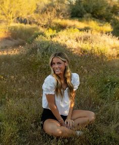 a beautiful young woman sitting in the grass