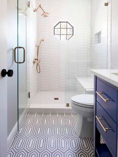 a bathroom with a toilet, sink and shower in it's own area that has geometric tiles on the floor