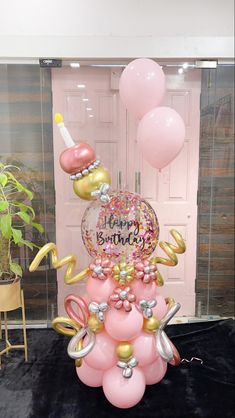 a pink and gold birthday cake with balloons