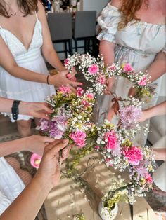 a group of women standing around a table with flowers in vases