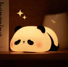 a panda bear lamp sitting on top of a wooden shelf next to a bookcase