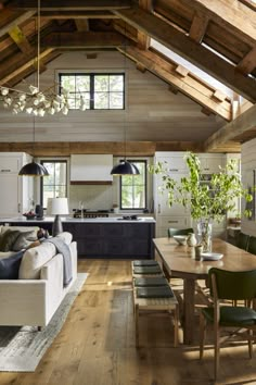 a living room filled with furniture next to a kitchen and dining room table on top of a hard wood floor