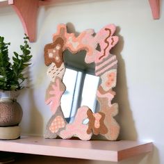 a mirror sitting on top of a wooden shelf next to a potted green plant