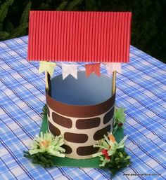 a paper cup with a house on it sitting on top of a blue and white checkered table cloth