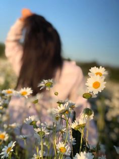 a woman standing in a field of daisies