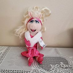 a stuffed animal doll with blonde hair and blue eyes sitting on a lace doily