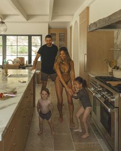 a man and two children are standing in the kitchen with an adult looking at them