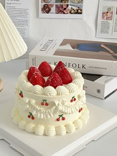 a white cake sitting on top of a table next to a lamp and bookcase