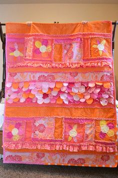 an orange and pink quilt hanging from a rack