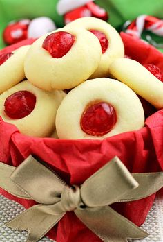 some cookies with jelly on them in a red bow sitting in a bowl next to candy canes