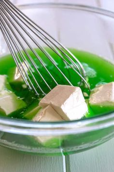 a bowl filled with green liquid and marshmallows