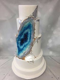 a white cake with blue and gold designs on it's side, sitting on a pedestal