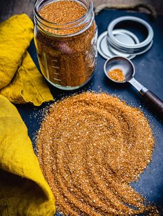 a jar filled with mustard sitting on top of a table next to a measuring spoon