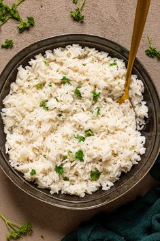 white rice in a bowl with a wooden spoon on the side and green napkins next to it