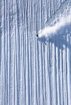 a person riding skis down a snow covered slope in the middle of the day