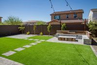 a backyard with green grass and brick pavers