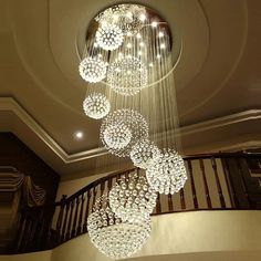 a chandelier hanging from the ceiling in a room with stairs and railings