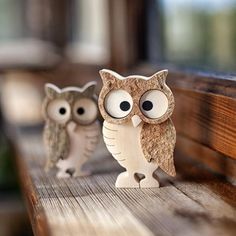 two little owls sitting on top of a wooden bench