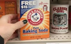 a hand is pointing at some baking sodas on the shelf in a store aisle