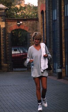 a woman is walking down the street with her cell phone