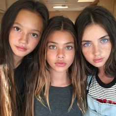 three girls are posing for the camera with freckles on their face and one girl has blue eyes