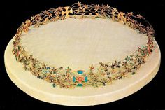 an elaborately decorated gold and blue tiara on a white cloth covered platter