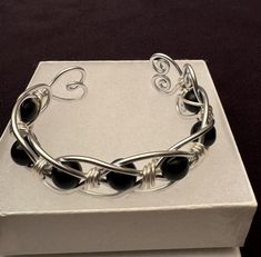 Handmade Hypoallergenic Aluminum Wire Wrapped Obsidian Bead Bracelet. Obsidian (Root Chakra). A Strongly Protective stone, known for its ability to Block, Absorb, and Transform negative energy. Truth-enhancing, Brings clarity to the mind and Clears confusion. Promotes qualities of compassion, strength and increases self-control. Aluminum symbolizes flexibility and versatility due to its malleable nature. This light weight metal will never tarnish or discolor. It is also hypoallergenic.and does not cause skin allergies. Makes a wonderful Valentine's Day Gift, Mother's Day Gift, or maybe even a Gift for yourself! Gift for any occasion, JUST BECAUSE - GIFTS OF LOVE! CARE INSTRUCTIONS: I recommend not wearing while exercising, showering or swimming. Use warm soapy water to clean then dry with Adjustable Cuff Bracelet With Round Beads For Gift, Adjustable Cuff Bracelet With Round Beads As Gift, Gift Adjustable Cuff Bracelet With Round Beads, Adjustable Round Beads Cuff Bracelet As Gift, Modern Beaded Bracelet With Black Beads As Gift, Nickel-free Modern Beaded Bracelets As Gift, Modern Nickel-free Beaded Bracelets For Gifts, Adjustable Onyx Bracelet Gift, Onyx Bracelets With Black Beads As Gift