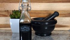 a bottle of coffee sitting on top of a counter next to a mortar and bowl