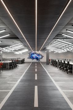 an empty office space with desks and chairs in it, along with lights on the ceiling