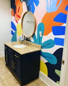 a bathroom with colorful wallpaper and vanity mirror