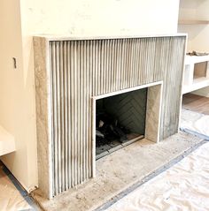 an unfinished fireplace in the middle of a room with white walls and flooring on top of it