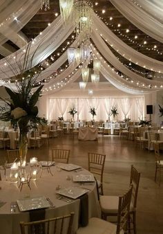 a banquet hall with tables, chairs and chandeliers on the ceiling is lit by lights