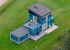 an aerial view of a blue house with solar panels on it's roof and balcony